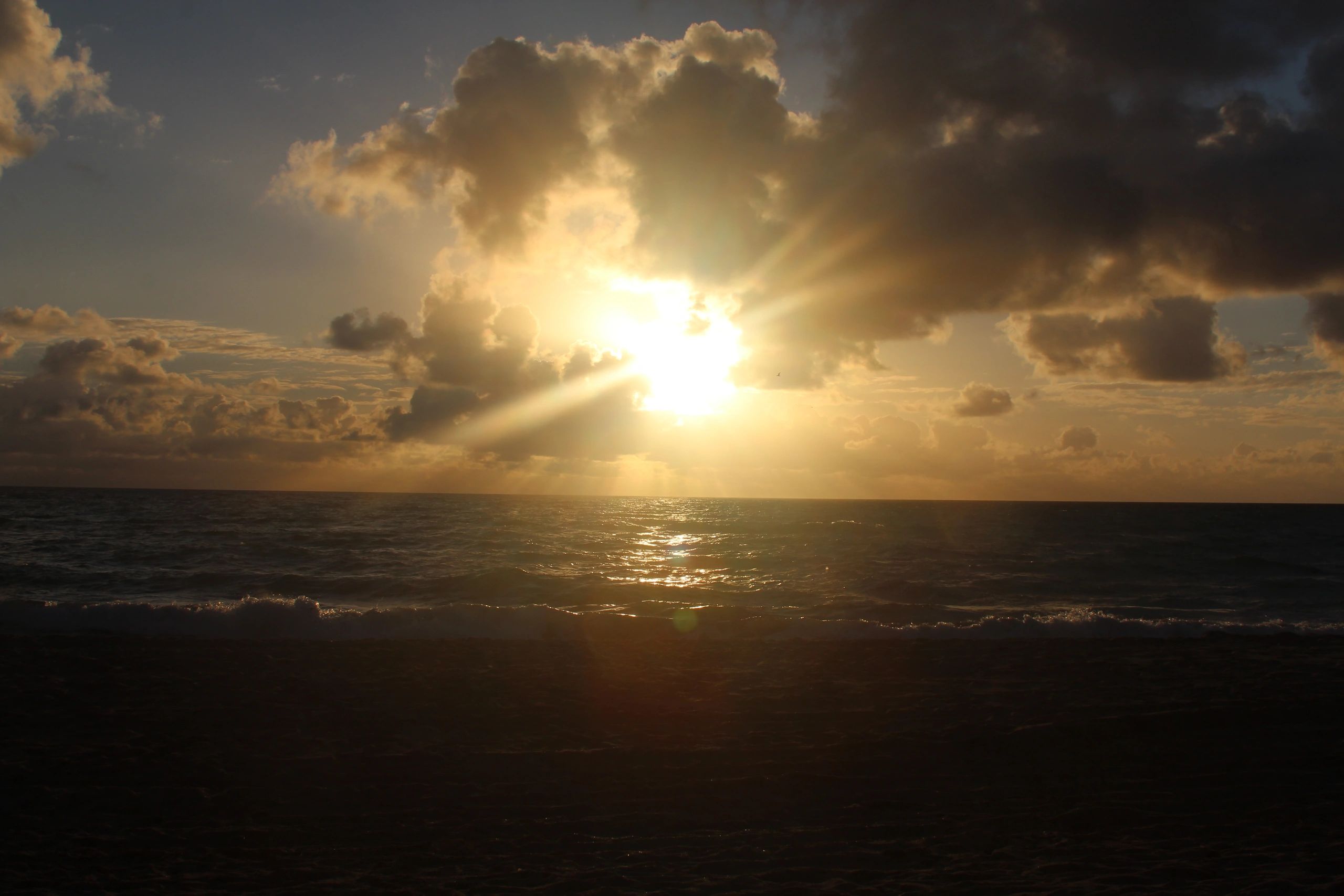 Wide sandy beach with calm water and pastel sky