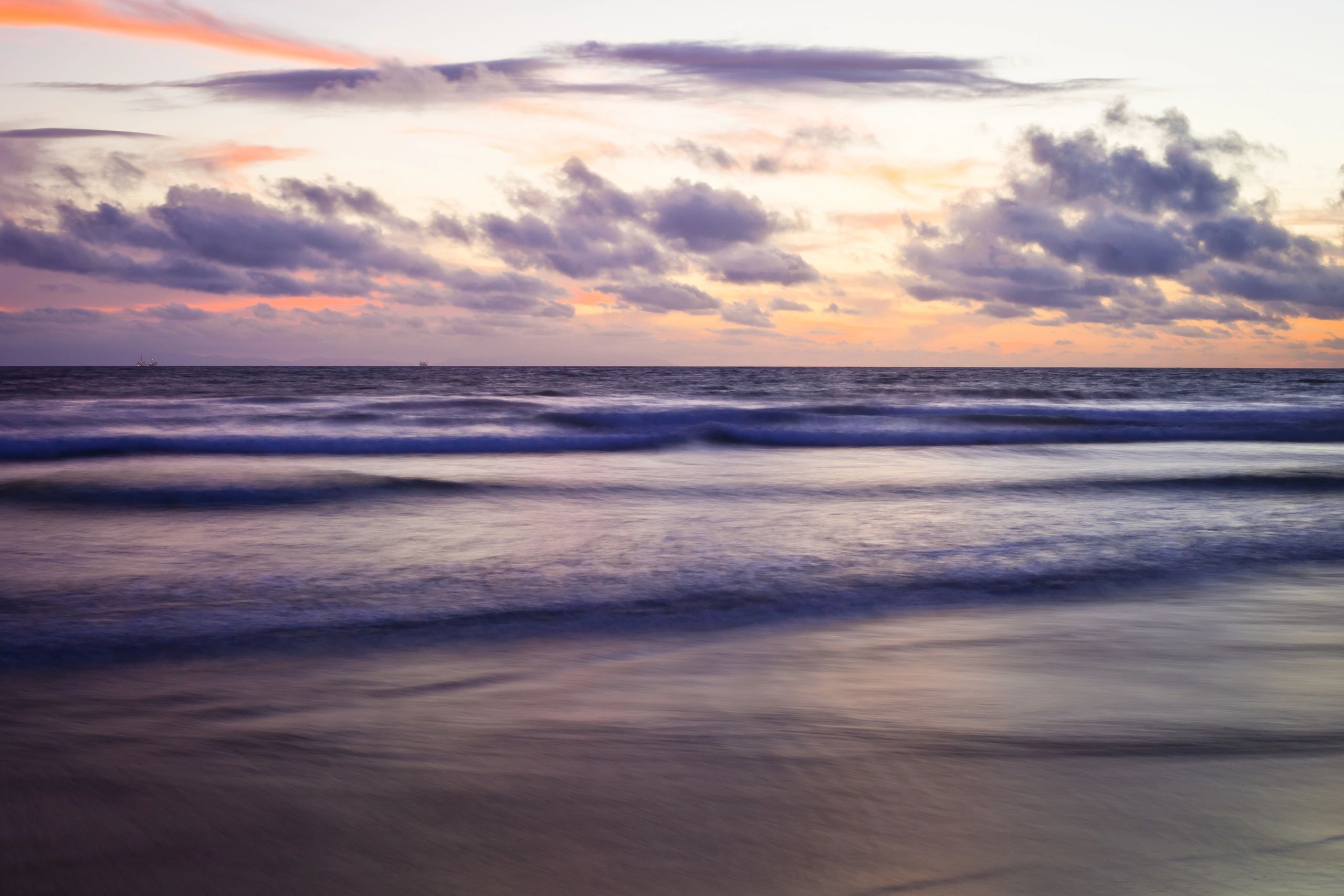 Beach shoreline at sunset with deep blue water and glowing sky