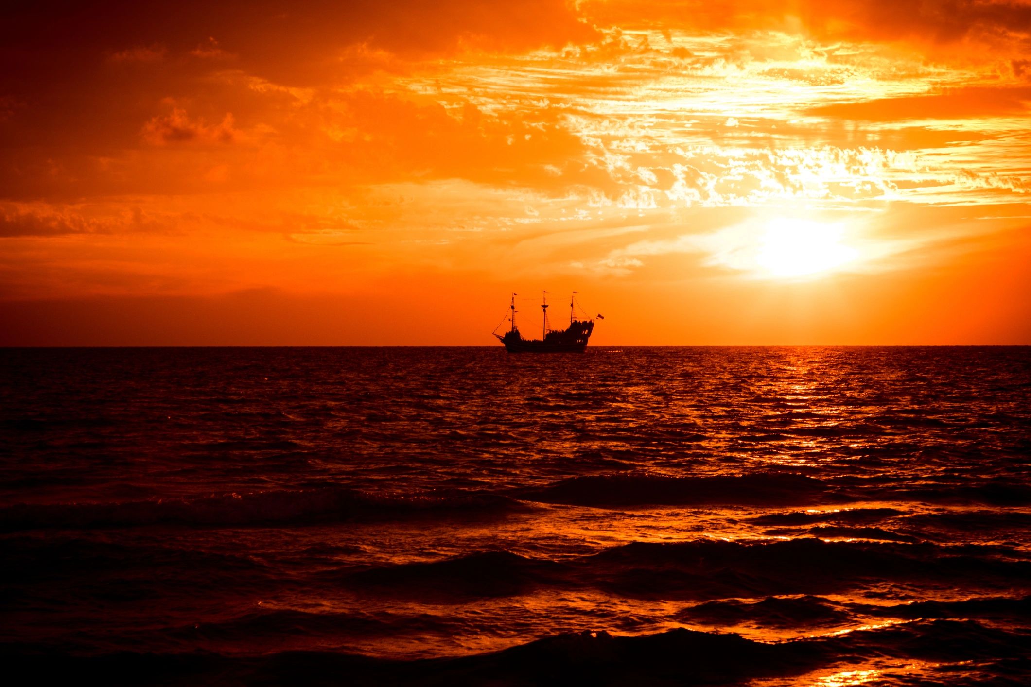 Coastal sunset scene with sailboat silhouette